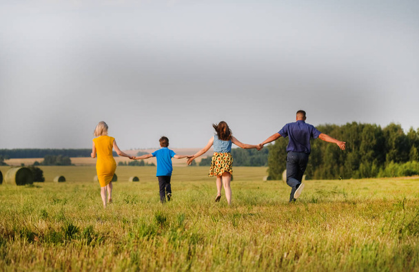 mamá, papá, hijo e hija corriendo a través del campo
 - Foto, imagen
