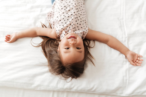 Pretty little cute asian girl at home indoors lies on bed - Fotó, kép