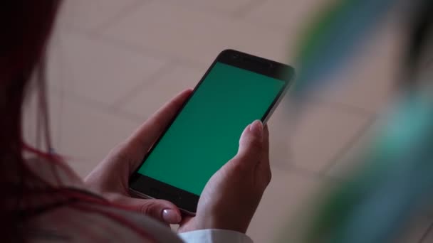 girl holding a smartphone in the hands of a green screen on floor tiles background - Filmagem, Vídeo