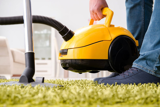 Man cleaning the floor carpet with a vacuum cleaner close up - Foto, afbeelding
