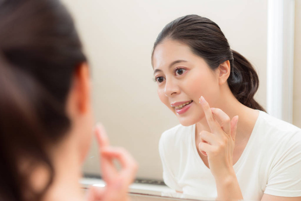 smiling young woman applying face cream on finger - Photo, Image