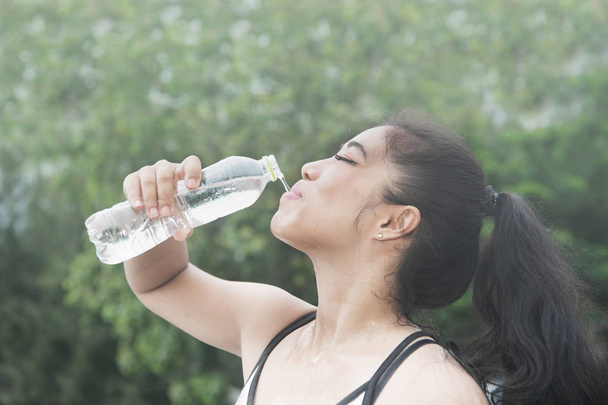 Σπορ ασιατική γυναίκα πόσιμο νερό εξωτερική μετά την άσκηση.  - Φωτογραφία, εικόνα