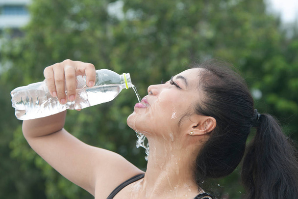 sportliche asiatische Frau trinkt nach dem Sport Wasser im Freien.  - Foto, Bild