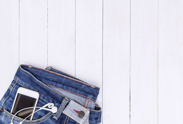 Telefon és a zenei fülhallgató Jean zsebében tér fehér másolás - Fotó, kép