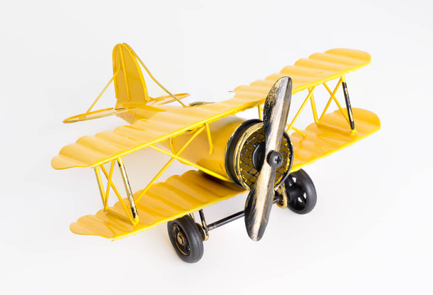 Avion jouet Vintage en métal jaune sur fond blanc
 - Photo, image