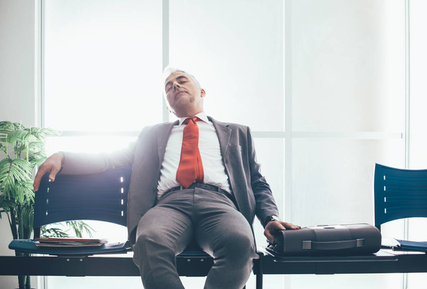 Tired businessman sleeping in waiting room - Fotó, kép