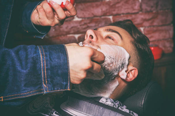 Shaving in the client Barbershop. Berber shaves client - Valokuva, kuva
