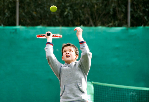 Little tennis player on a blurred green background - Photo, Image