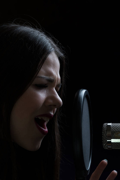Mooi meisje zingen In opnamestudio met microfoon - Foto, afbeelding