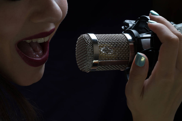 Singer in front of a microphone. Isolated on a dark background - Foto, Imagen