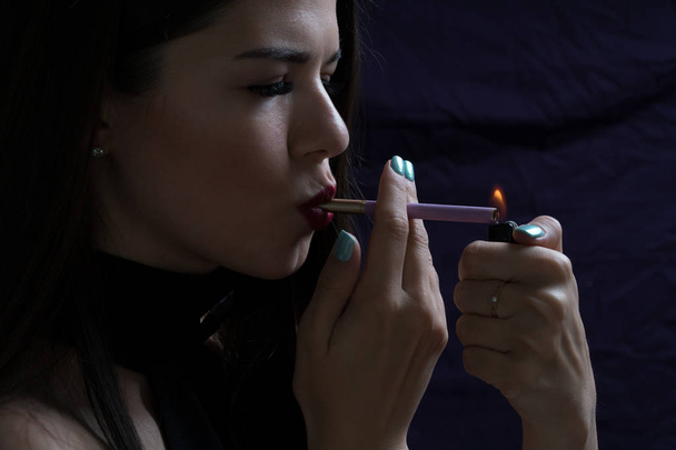 Portrait of the beautiful elegant girl smoking cigarette isolated on dark background - Fotografie, Obrázek
