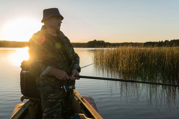 ein Mann fischt bei Sonnenuntergang von einem Boot aus - Foto, Bild