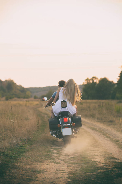 Νεαρό ζευγάρι σε μια μοτοσικλέτα στο πεδίο - Φωτογραφία, εικόνα