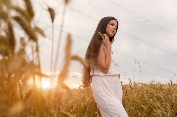 Una chica con un traje blanco de verano está de pie en un campo de trigo
 - Foto, Imagen