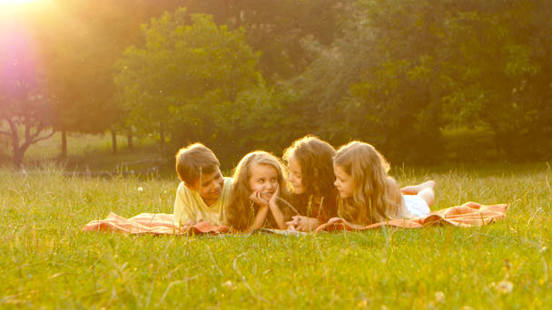 Dzieci wertować książki w ogrodzie na trawniku w letni dzień - Materiał filmowy, wideo