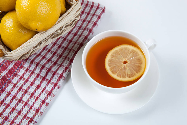 Nature morte de citrons frais dans un panier et une tasse de thé
 - Photo, image