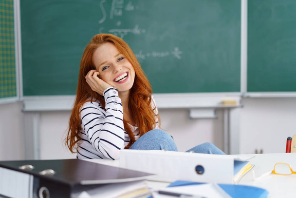 Young cheerful woman talking on phone in classroom - Φωτογραφία, εικόνα