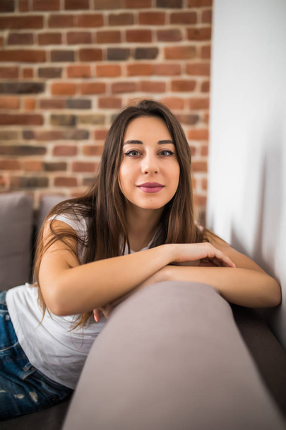 Happy young woman lying on couch and relaxing at home, casual style - Photo, Image