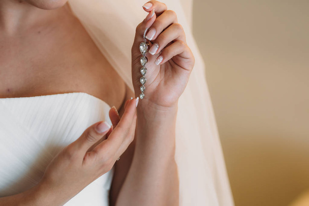 Earrind in the hands of the bride. Concept of jewelry - Fotografie, Obrázek