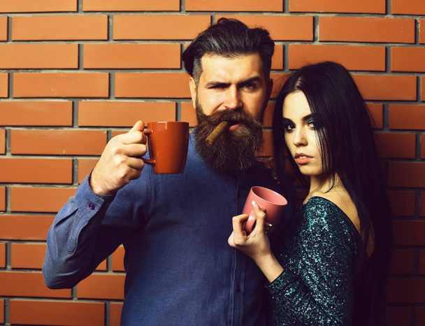 bearded man and pretty sexy woman with cigar, tea cups - Фото, изображение