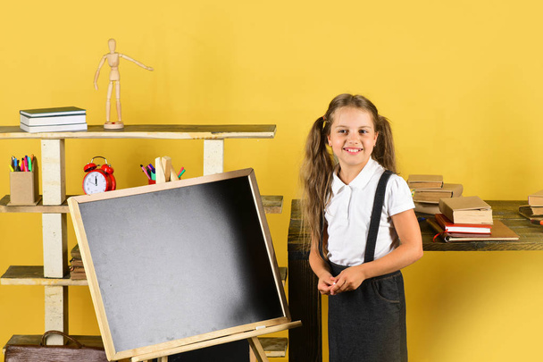 Girl in classroom stands near blackboard, copy space - Φωτογραφία, εικόνα