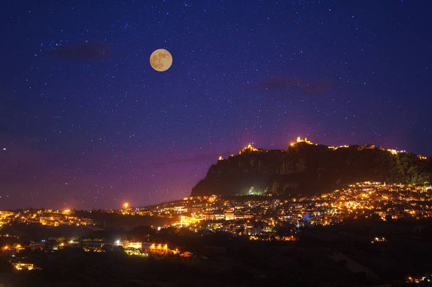 San Marino na pełni księżyca nocy zdjęcie z scenic niebo i jasne światła miasta noc. - Zdjęcie, obraz
