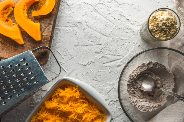 Grater, grated pumpkin, flour on a white table for making pancakes - Foto, Bild