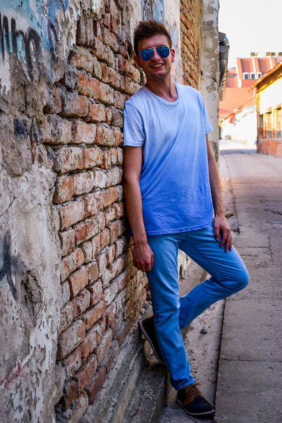 A fiatalember pózol egy rusztikus fal mellett - Fotó, kép