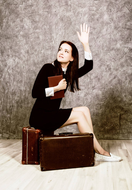 Retro woman with suitcase reading book waiting for a meeting, vintage style. - Zdjęcie, obraz