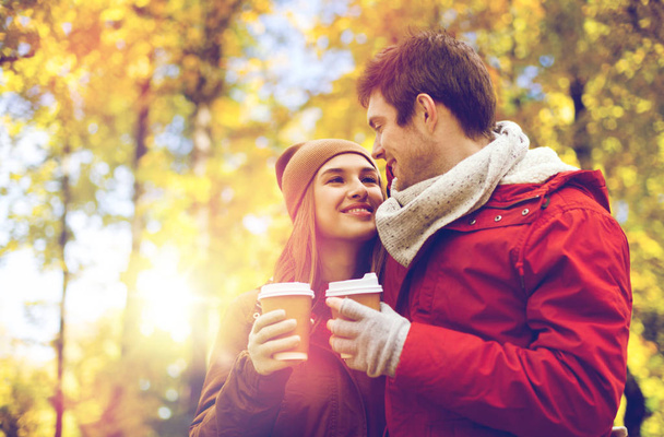happy couple with coffee walking in autumn park - Zdjęcie, obraz