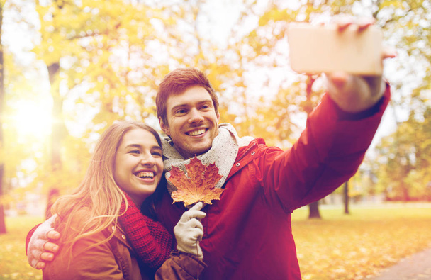 couple taking selfie by smartphone in autumn park - Фото, изображение