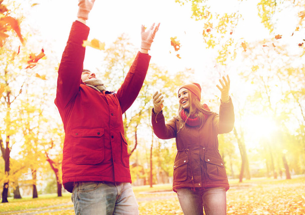 happy young couple throwing autumn leaves in park - Photo, Image