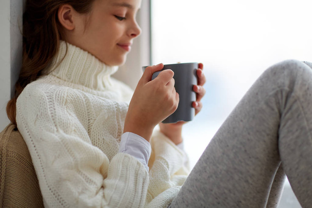 girl with tea mug sitting at home window - Zdjęcie, obraz