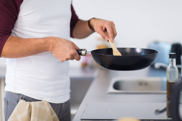 man with frying pan cooking food at home kitchen - Valokuva, kuva
