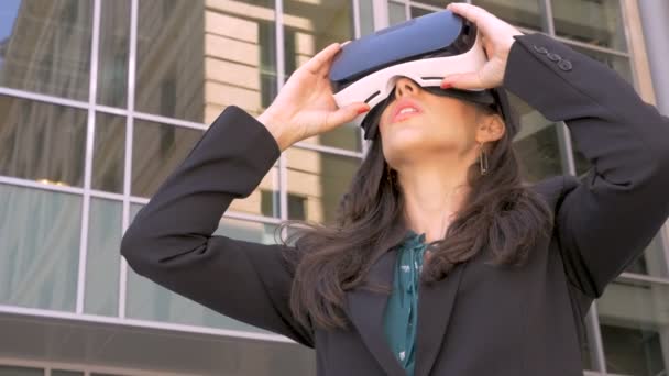 Female corporate executive using VR headset outside glass office building - Imágenes, Vídeo