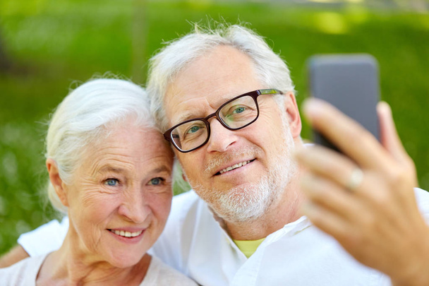 senior couple with smartphone taking selfie in summer - Photo, Image