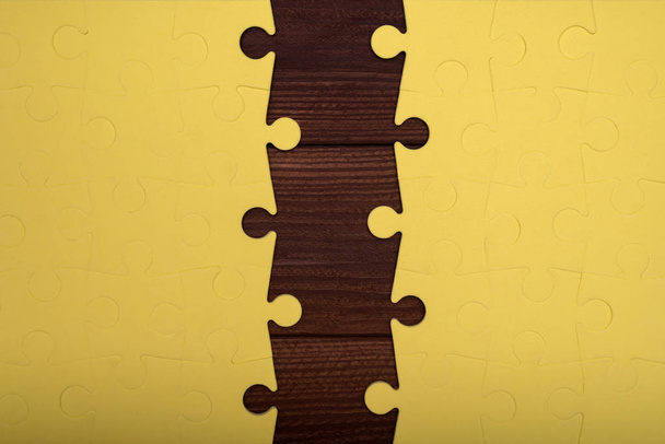 Due pezzi di un puzzle giallo su uno sfondo di legno
 - Foto, immagini