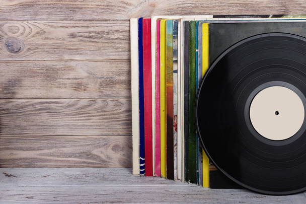Retro styled image of a collection of old vinyl record lp's with sleeves on a wooden background. Copy space. - Photo, image