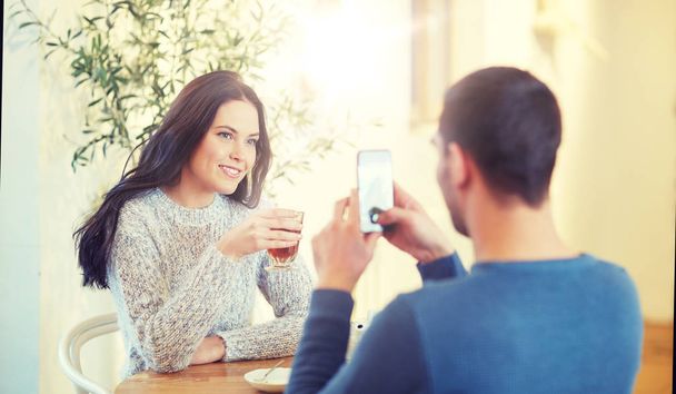 man taking picture of woman by smartphone at cafe - Φωτογραφία, εικόνα