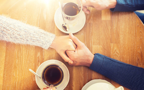 close up of couple holding hands at restaurant - Photo, Image