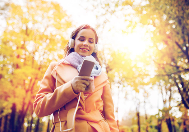 woman with smartphone and earphones in autumn park - Fotoğraf, Görsel