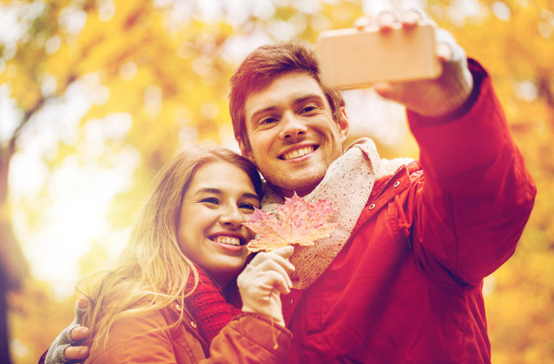 couple taking selfie by smartphone in autumn park - Foto, afbeelding
