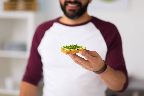 man eating avocado sandwich at home kitchen - Фото, зображення