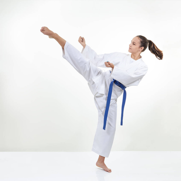 A high circular kick kicks the athlete in karategi - Photo, Image