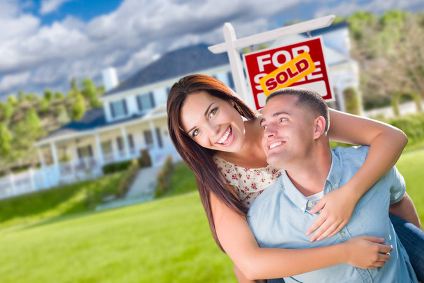 Verspielt aufgeregtes Militär-Paar vor Haus mit verkauftem Immobilienschild. - Foto, Bild