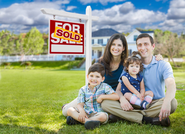 junge Familie mit Kindern vor benutzerdefinierten Haus und verkauft zum Verkauf Immobilienschild. - Foto, Bild