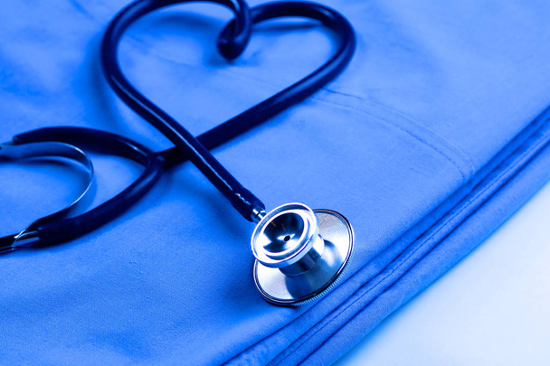 een stethoscoop vormgeving een hart en een Klembord op een medische uniforme, close-up - Foto, afbeelding