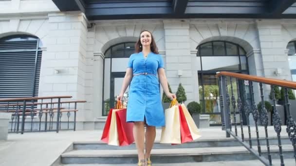 Νεαρή γυναίκα ευτυχισμένη με περπάτημα από κατάστημα τσάντες για ψώνια - Πλάνα, βίντεο