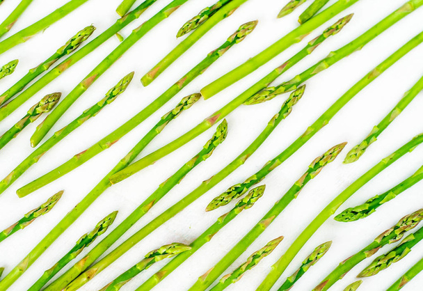 Fresh green asparagus shoots pattern, top view. Isolated over white. Food background asparagus top view pattern - Фото, изображение