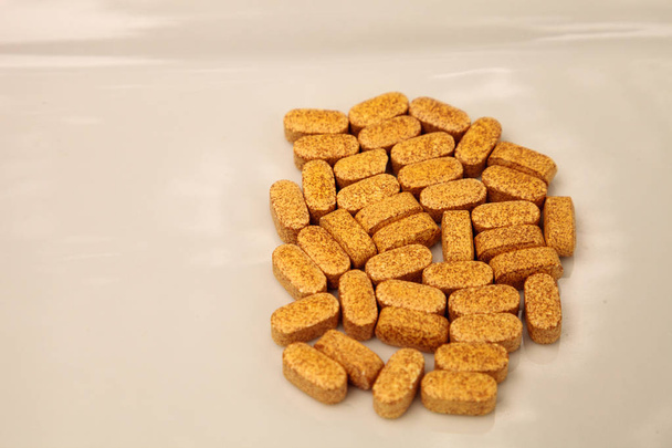 Χρυσό gel κάψουλα βιταμίνη Β που εμφανίζεται σε μια λευκή επιφάνεια. - Φωτογραφία, εικόνα